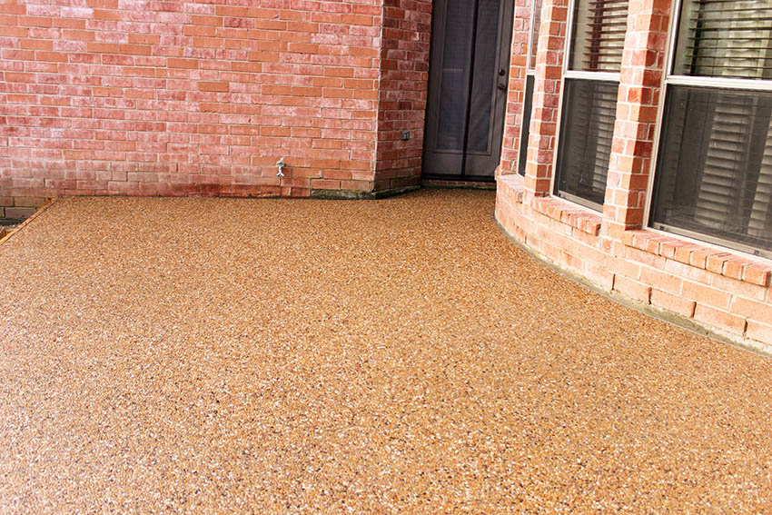 Aggregate pebble patio behind brick home