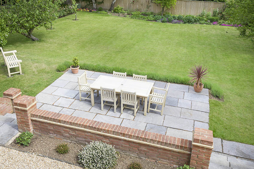 Large bluestone pavers patio with outdoor dining table brick wall