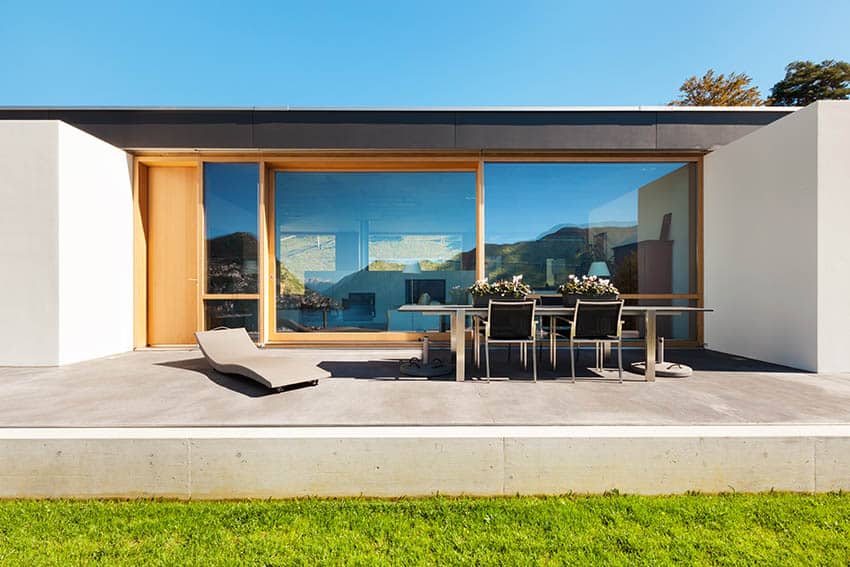 Raised concrete patio on modern home backyard with outdoor dining table