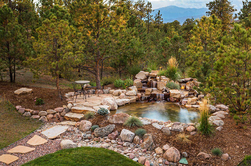 Raised flagstone patio above water feature pond and waterfall