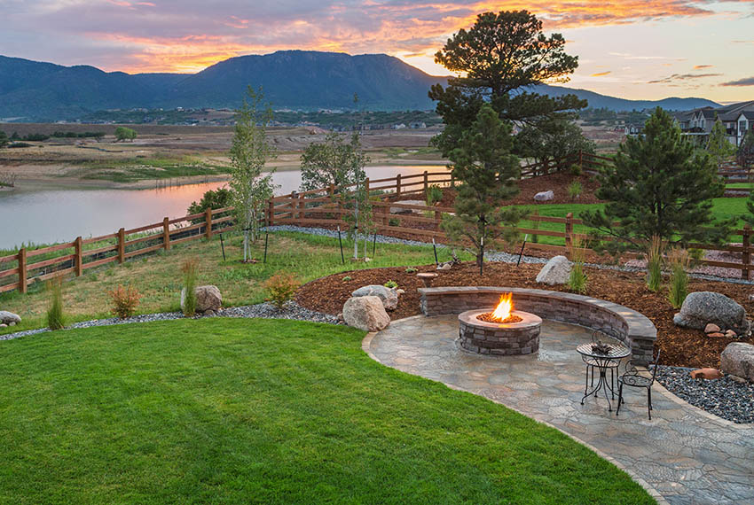 Stamped design concrete fire pit patio with stone bench and waterfront river views