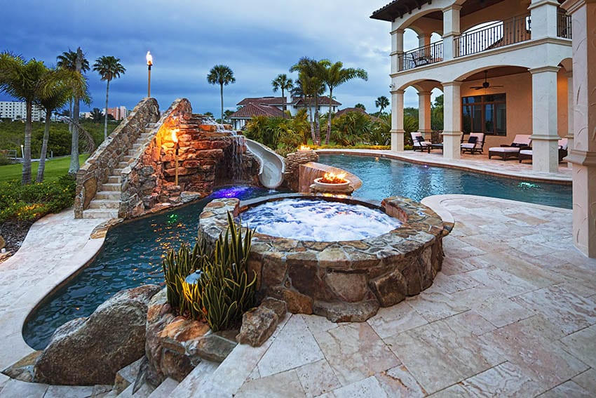 Stamped style concrete pool deck patio with elevated hot tub water slide