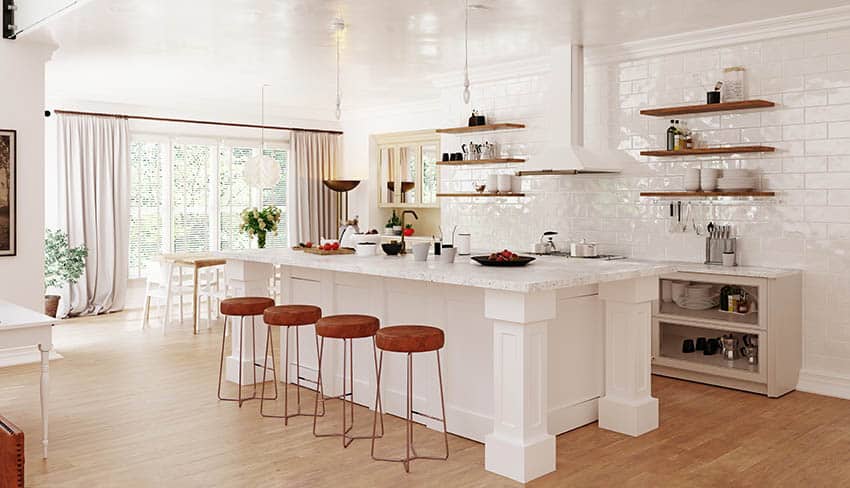 White cabinet kitchen with white quartz countertops island with legs and wall of large subway tile