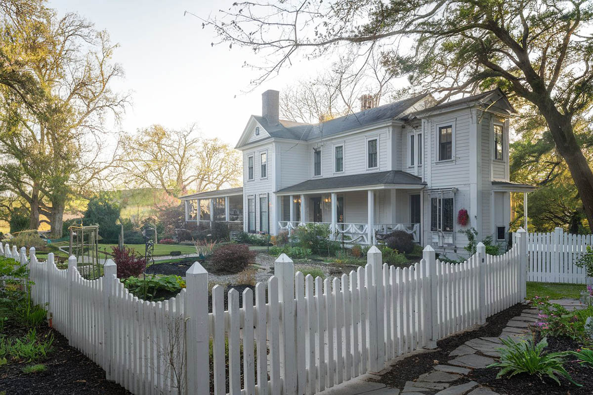 White curved fence with traditional shiplap home
