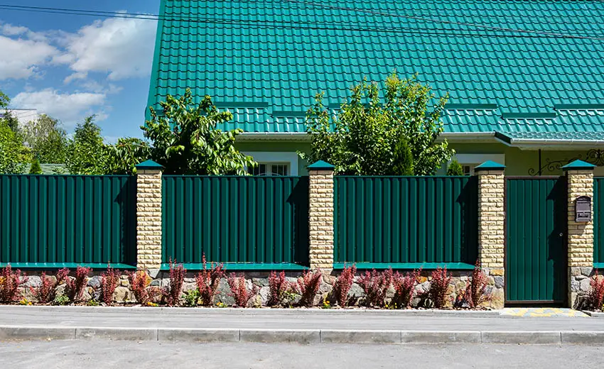 Green metal and stone fence