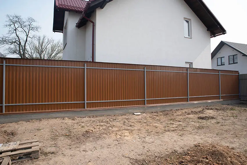 Home backyard with brown corrugated panel fence with steel supports
