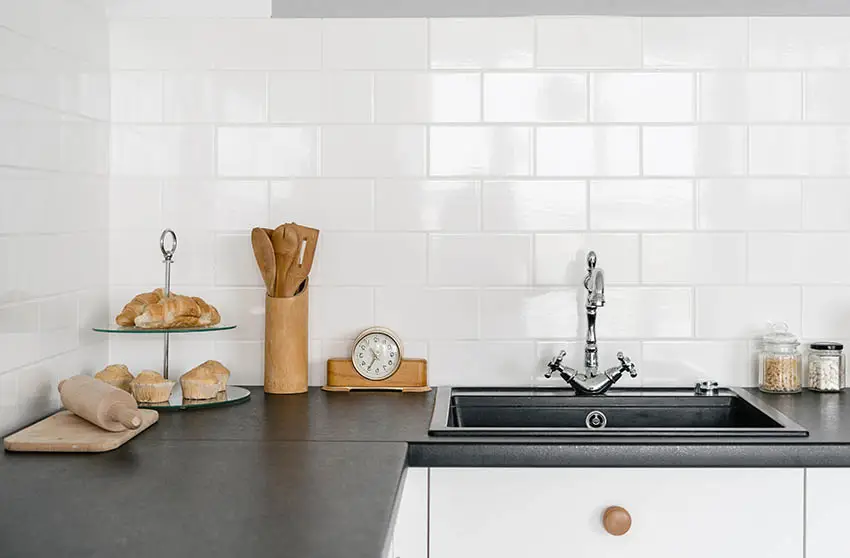 Kitchen with black leathered countertop white subway tile