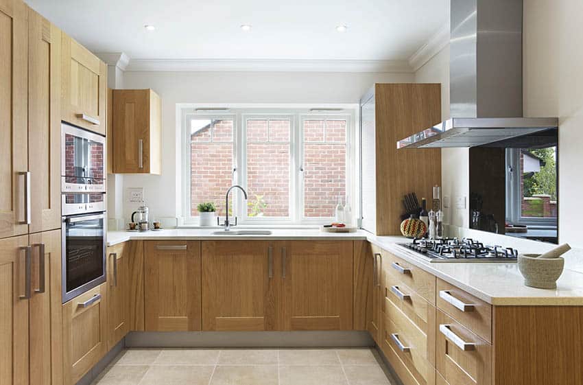 Kitchen with oak-like cabinets, white window and travertine floors