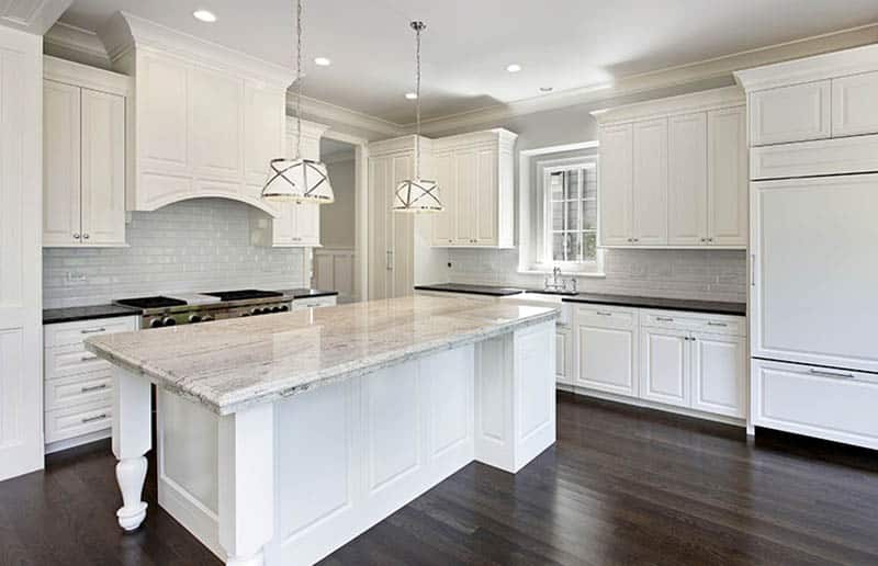 Kitchen with white black granite counters subway tile backsplash white cabinets and drum pendant lights