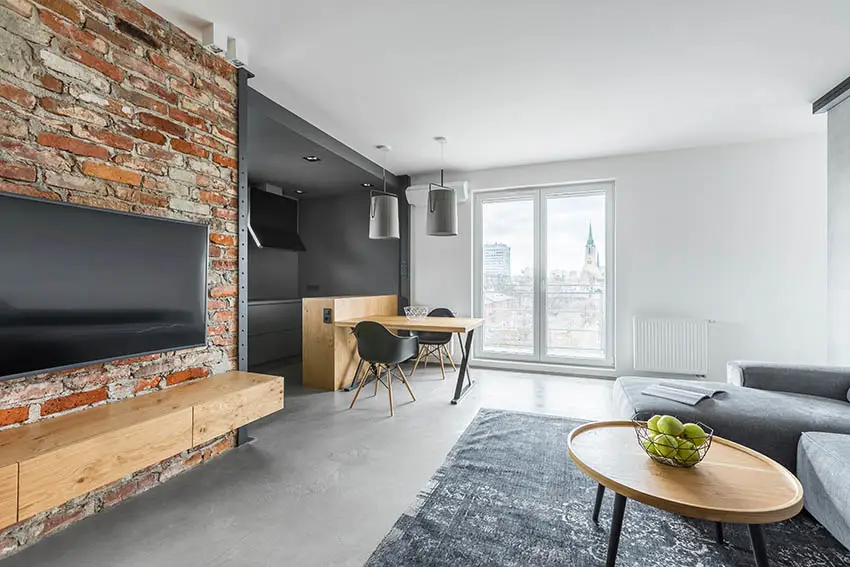 Room with grey concrete flooring and rough brick accent wall area