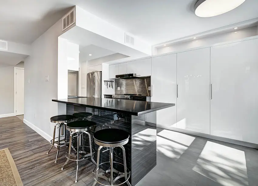 Modern kitchen with black laminate countertop peninsula white gloss cabinets