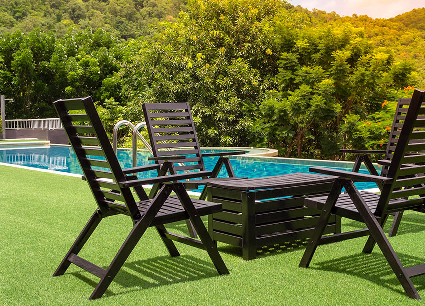 Grass around pool with outdoor chairs and crate table