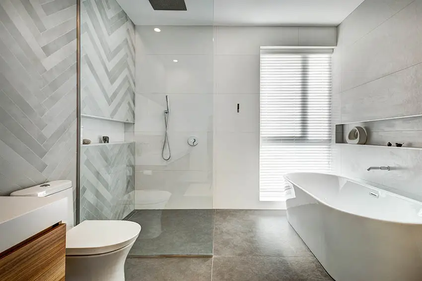 Bathroom with freestanding tub, chevron patterned tiles and window with blinds