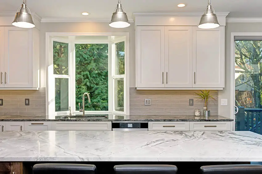 Beautiful kitchen with two tone dekton countertops tile backsplash large island bay window silver pendant lights