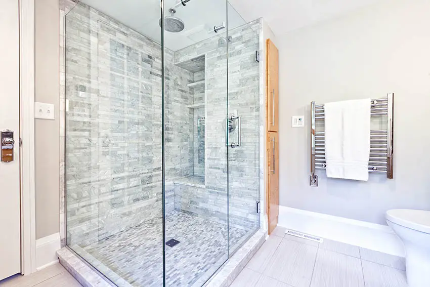 Bathroom with glas shower partition, towel rack and marble flooring