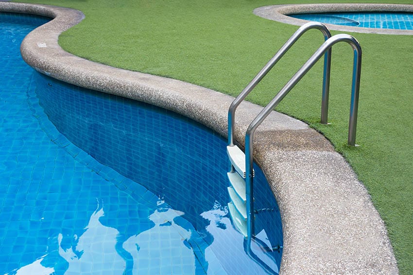 Curved swimming pool with artificial turf patio border