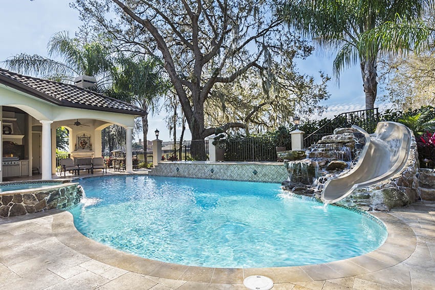 Custom swimming pool with travertine deck water feature waterfall slide