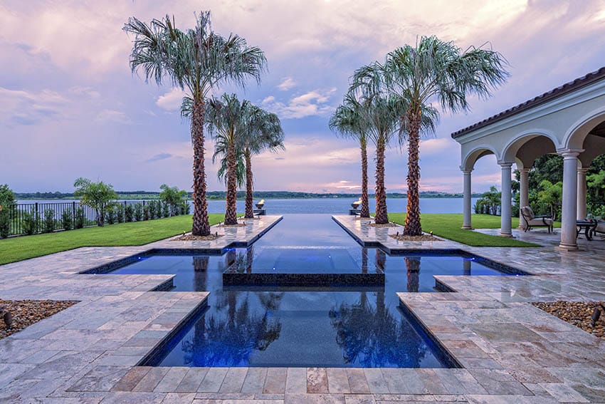 Custom tropical pool with travertine paver deck palm trees water views fire bowls