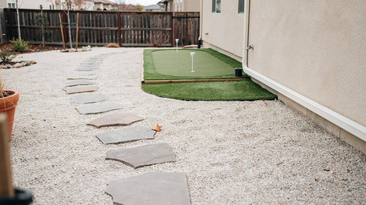 Pale gravel yard with flagstone stepping path leading to small turf green