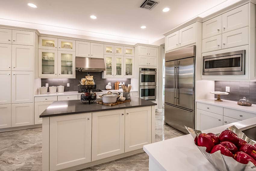 Kitchen with white cabinets, black countertops and backsplash