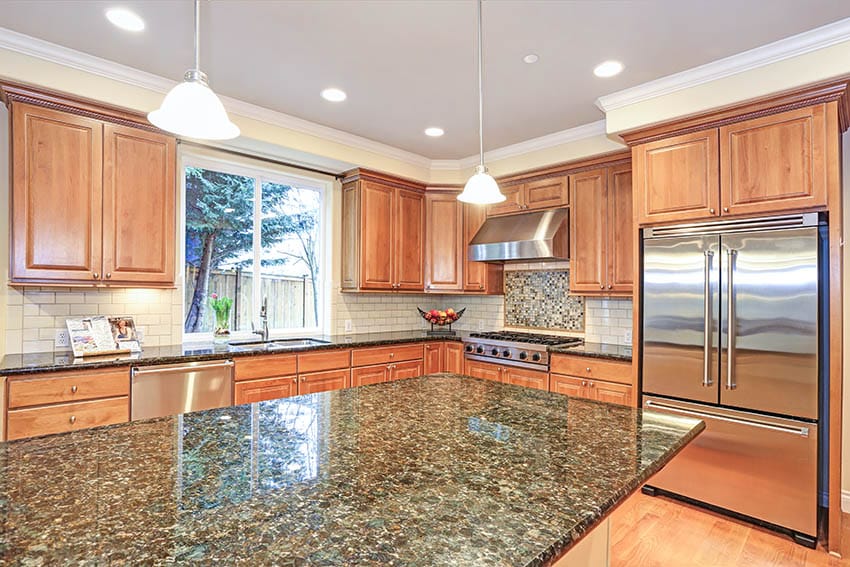 Kitchen with verde peacock green granite countertops wood cabinets