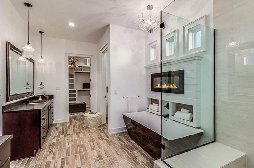 Luxury bathroom with porcelain wood tile floors black enamel tub gas fireplace chandelier