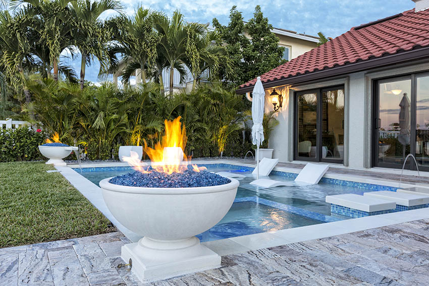 Marble swimming pool deck with fire pit pots tropical landscape