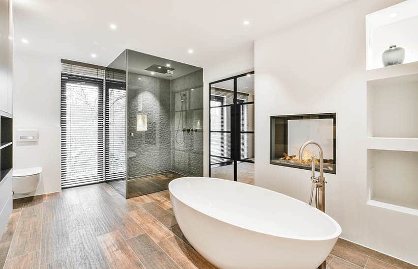 Master bathroom with wood look porcelain tile floors freestanding tub smoked glass walk in shower with rainfall head