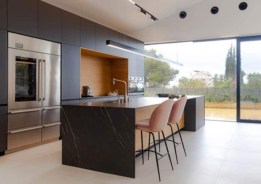 Modern kitchen with white ceramic tile flooring black cabinets black quartz waterfall countertops