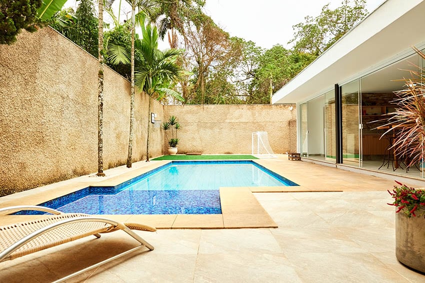 Modern soaking pool with large travertine surface palm trees high privacy wall