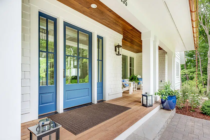 Blue front door with shingles walling and horizontal wooden ceiling