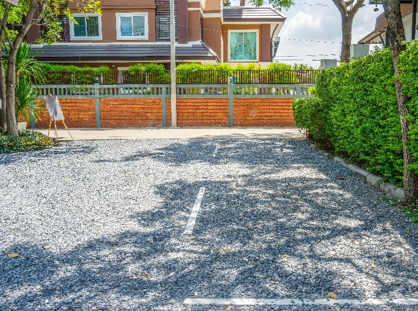 big brown house fronting gravel yard with trees on the side