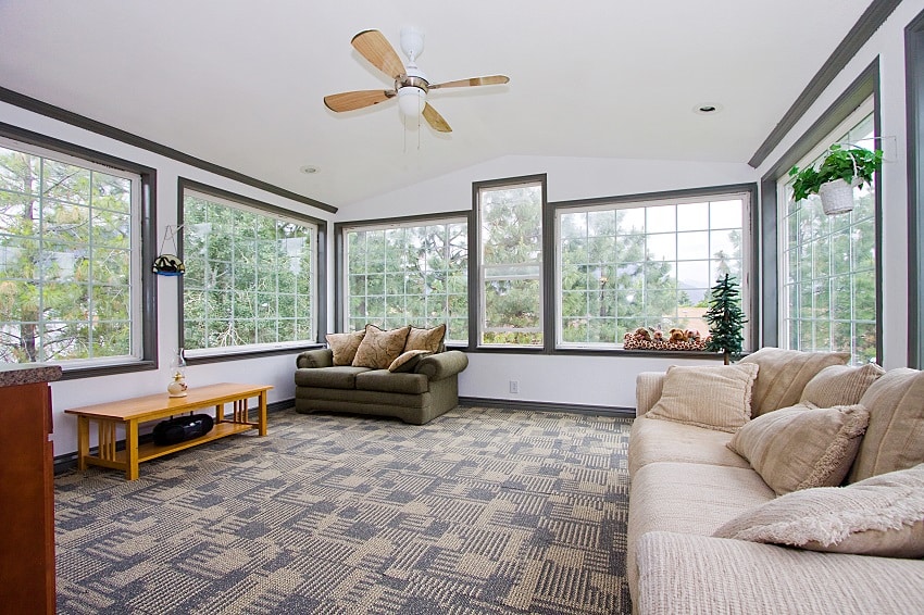 big sunroom in a house with ceiling fan sofa and plants