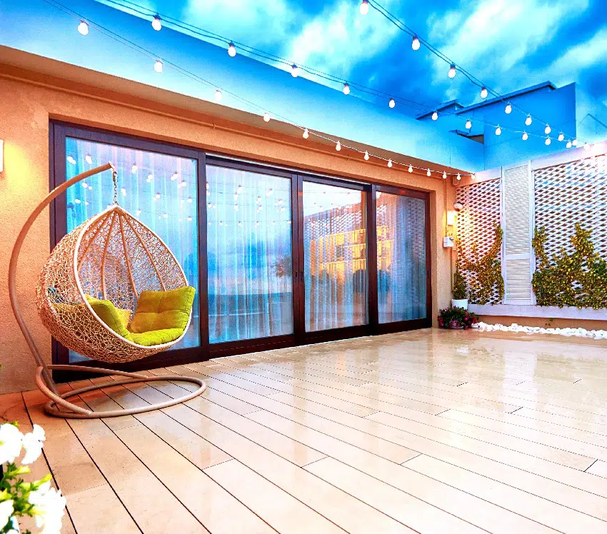 Wooden deck decorated with string lights and rattan swing