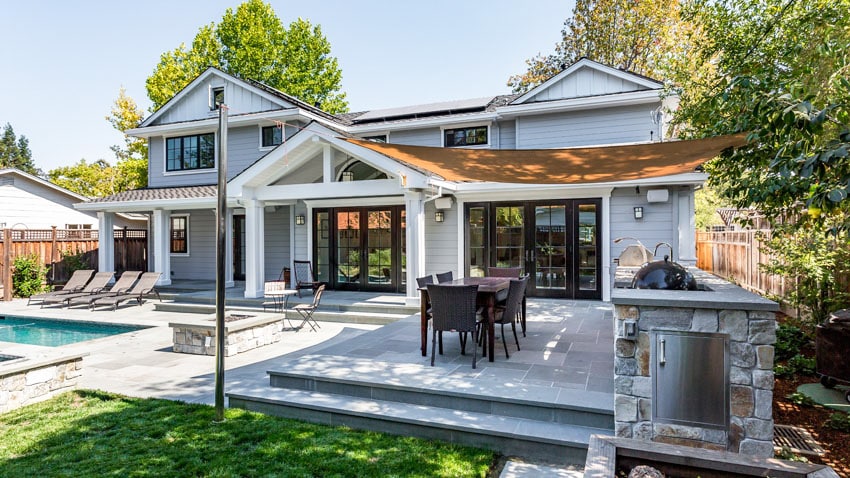 Elevated pool patio with outdoor kitchen grill and canopy cover