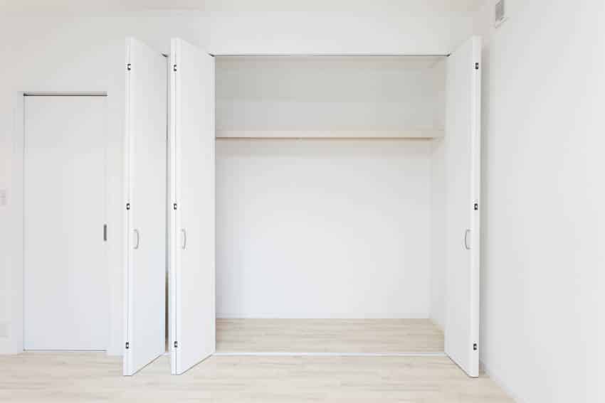 Empty closet with laminate flooring and white walls