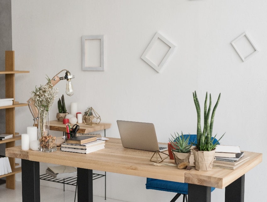  home office with white background wall decors office table with laptop books candles and office supplies