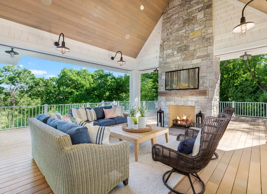 Huge outdoor wood deck with sconce lights, vaulted covering and stone fireplace