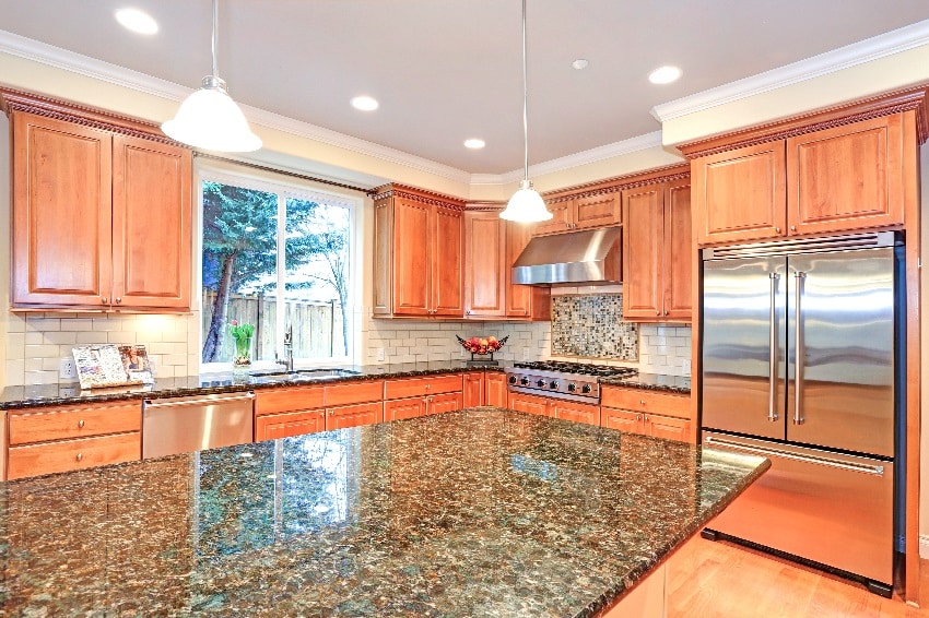 Kitchen with oak cabinets, off-white subway tile and black granite countertops