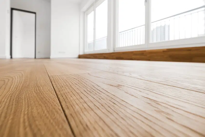 Laminate flooring in an empty room with large windows