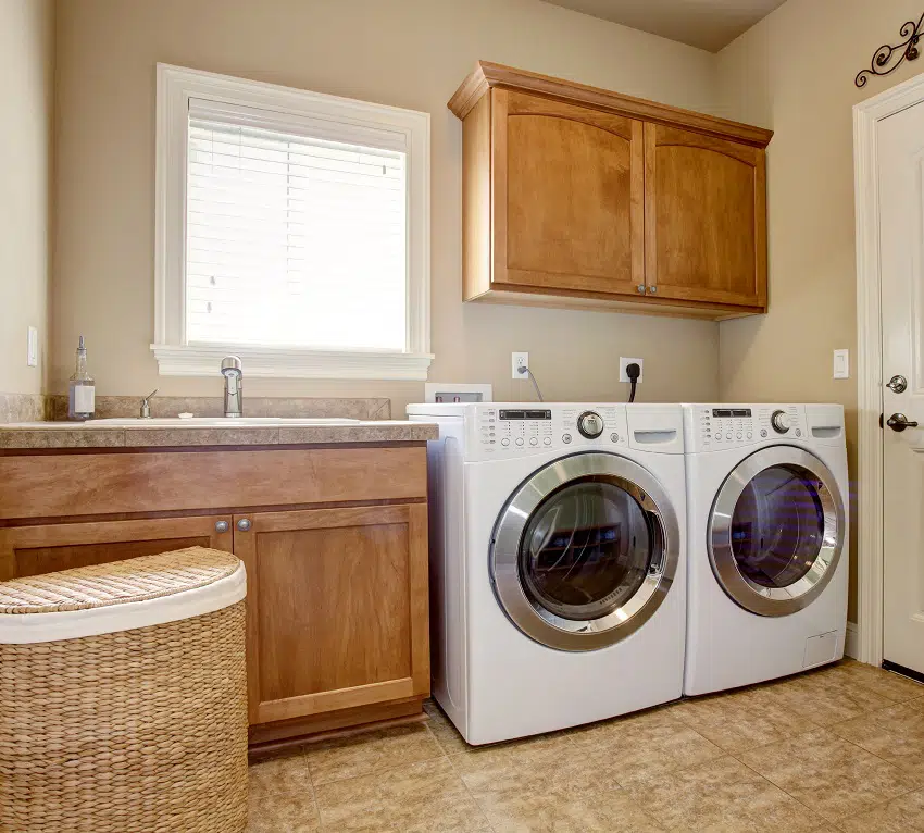laundry room with cream white wall paint washer dryer and wooden cabinets