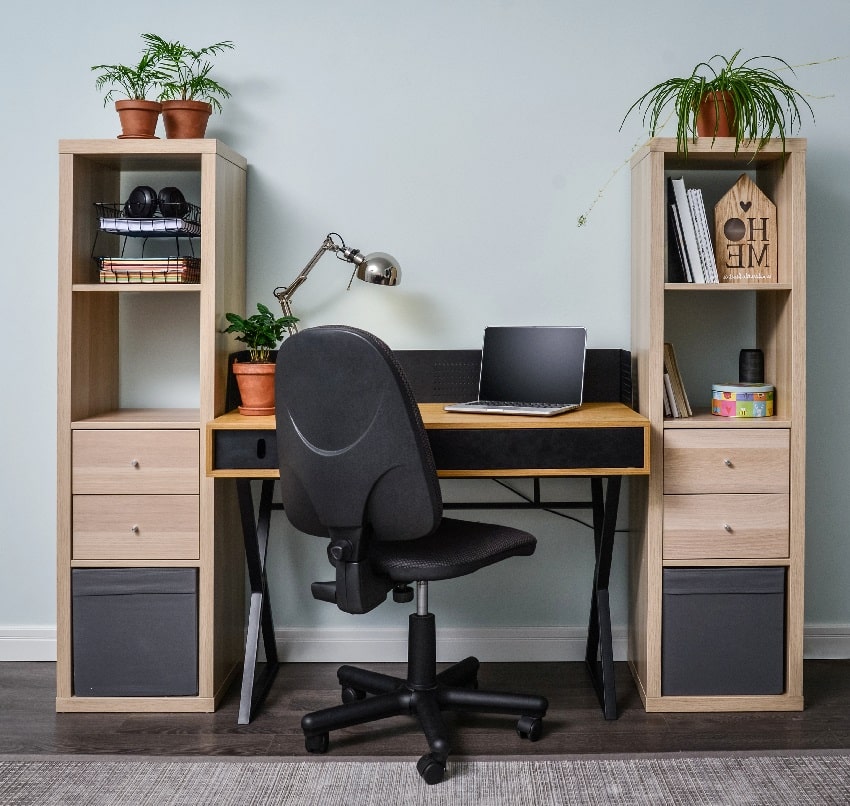 light cozy home office room with wooden bookcases, working desk laptop and black office chair