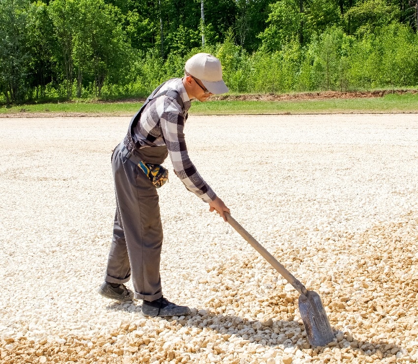 man levels gravel with a shovel