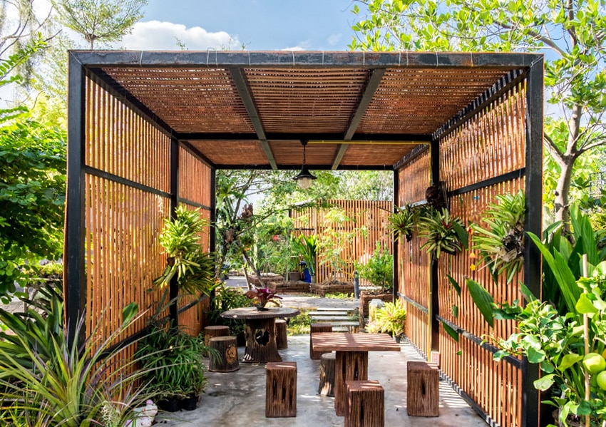 Modern backyard with pendant pergola lighting, thatch wall, and outdoor furniture