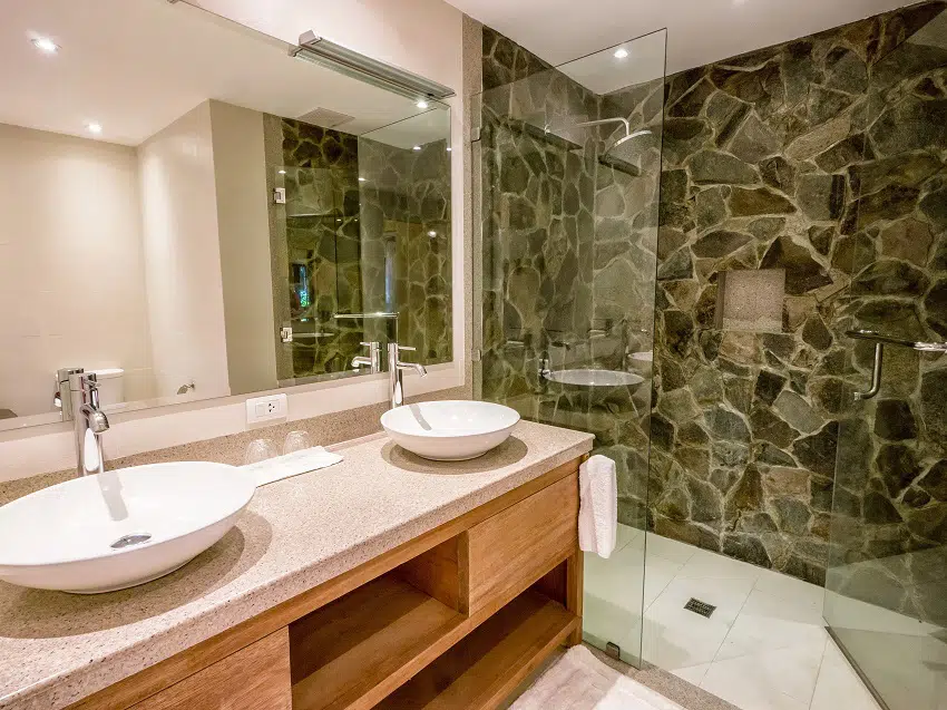 modern bathroom with two round white vessel sinks on granite counter natural stone and glass shower enclosure