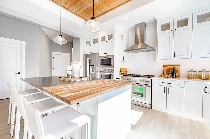 Modern farmhouse kitchen with butcher block wood countertops white cabinets wood ceiling feature