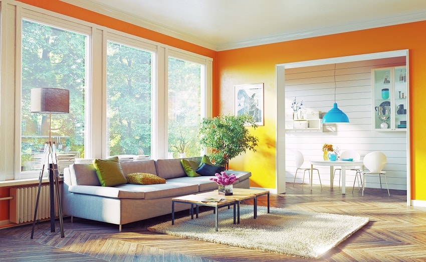 modernes Wohnzimmer Interieur mit gelb orange Wandfarbe Stehlampe und grüne Pflanze neben dem Sofa ist