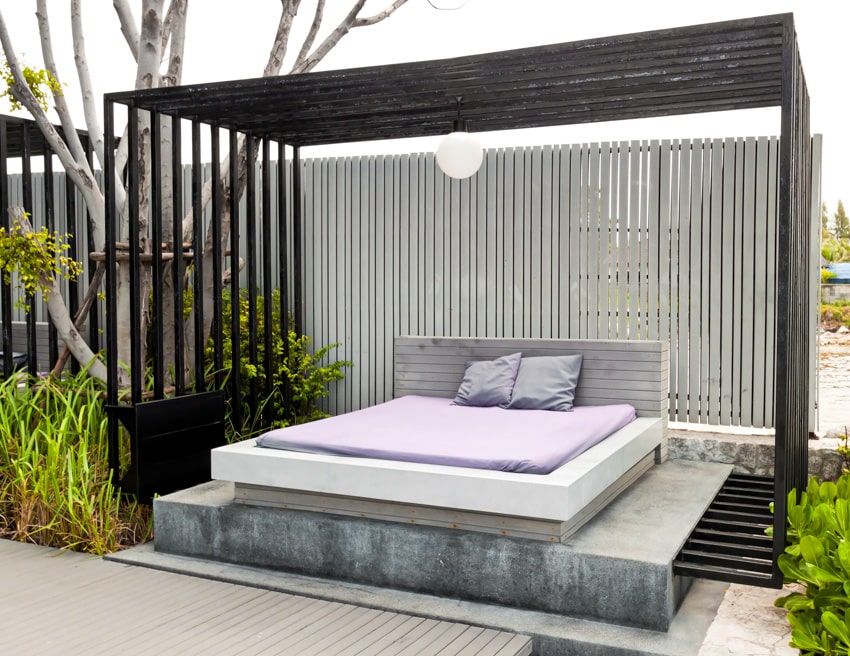 Modern style pergola with outdoor lounging bed, privacy slats, and overhead lighting