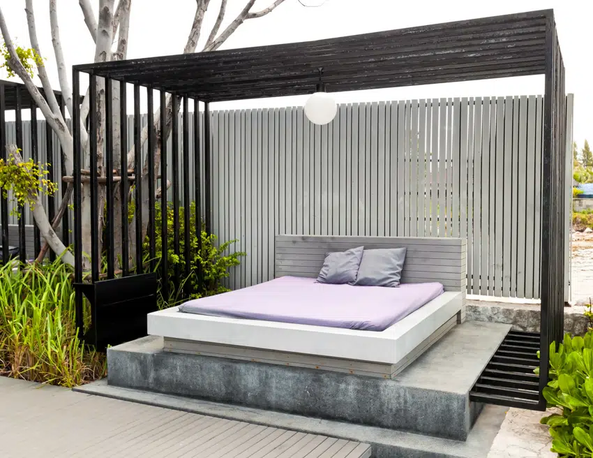 Modern pergola with outdoor lounging bed, privacy slats, and overhead lighting