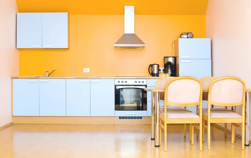 orange modern fitted kitchen with white cabinets yellow dining set and coffee maker